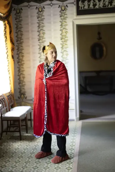 Person utkledd som kongelig figur med krone og rød kappe under vandreteateret «Oppdrag 1814» i Eidsvollsbygningen.