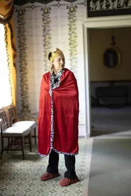 Person utkledd som kongelig figur med krone og rød kappe under vandreteateret «Oppdrag 1814» i Eidsvollsbygningen.