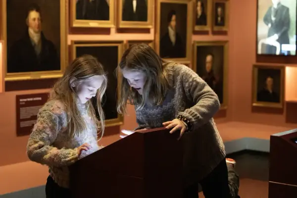 To barn utforsker en interaktiv skjerm i utstillingen i Demokratisenteret Wergelands hus på Eidsvoll 1814.