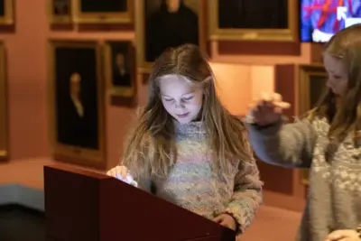 To barn utforsker en interaktiv skjerm i utstillingen i Demokratisenteret Wergelands hus på Eidsvoll 1814.