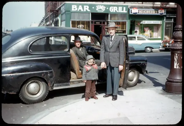 Three generations of Norwegians by a car on Lapskaus Boulevard in New York.