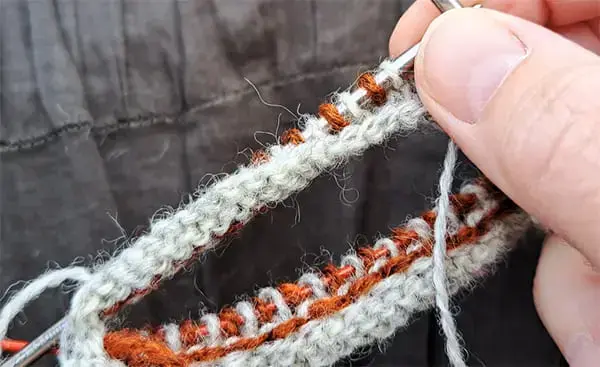 Varv 1. Börja med att sticka ett varv med varannan maska i färg 1 och varannan i färg 2.