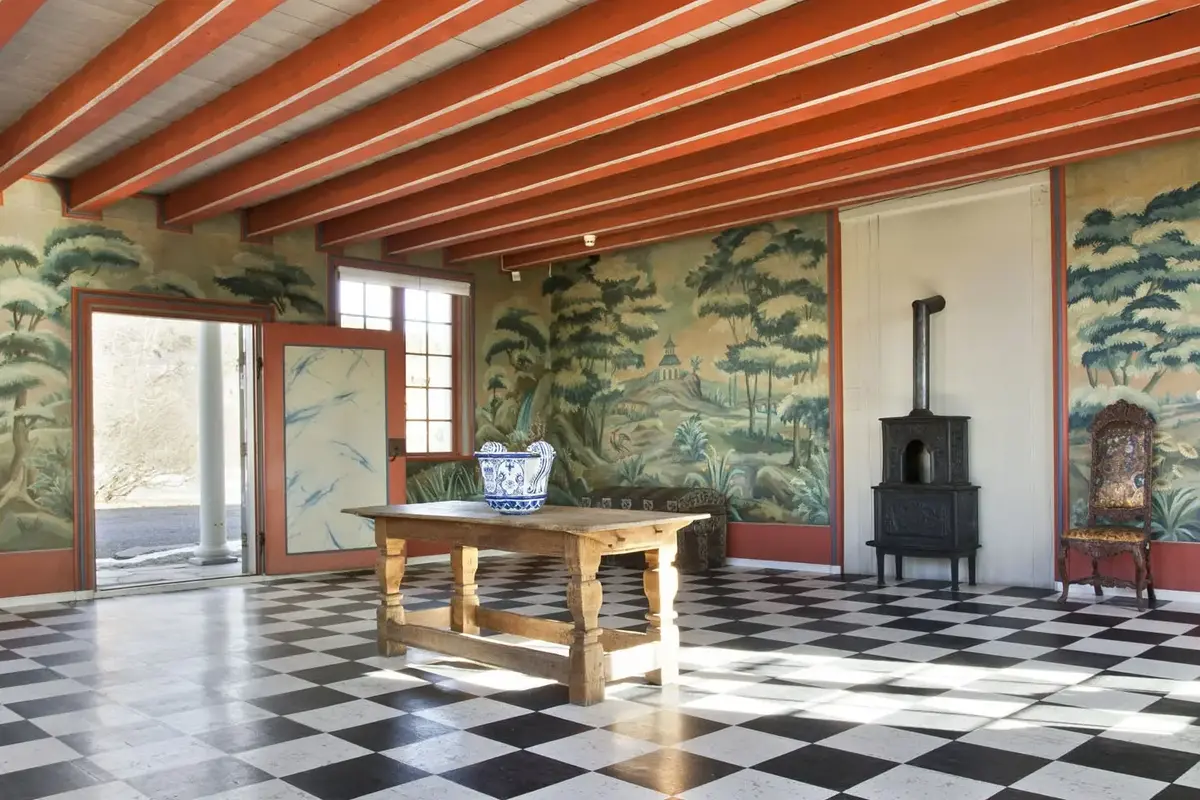 Foto av en sal med rutete gulv og veggmalerier på Linderud gård.