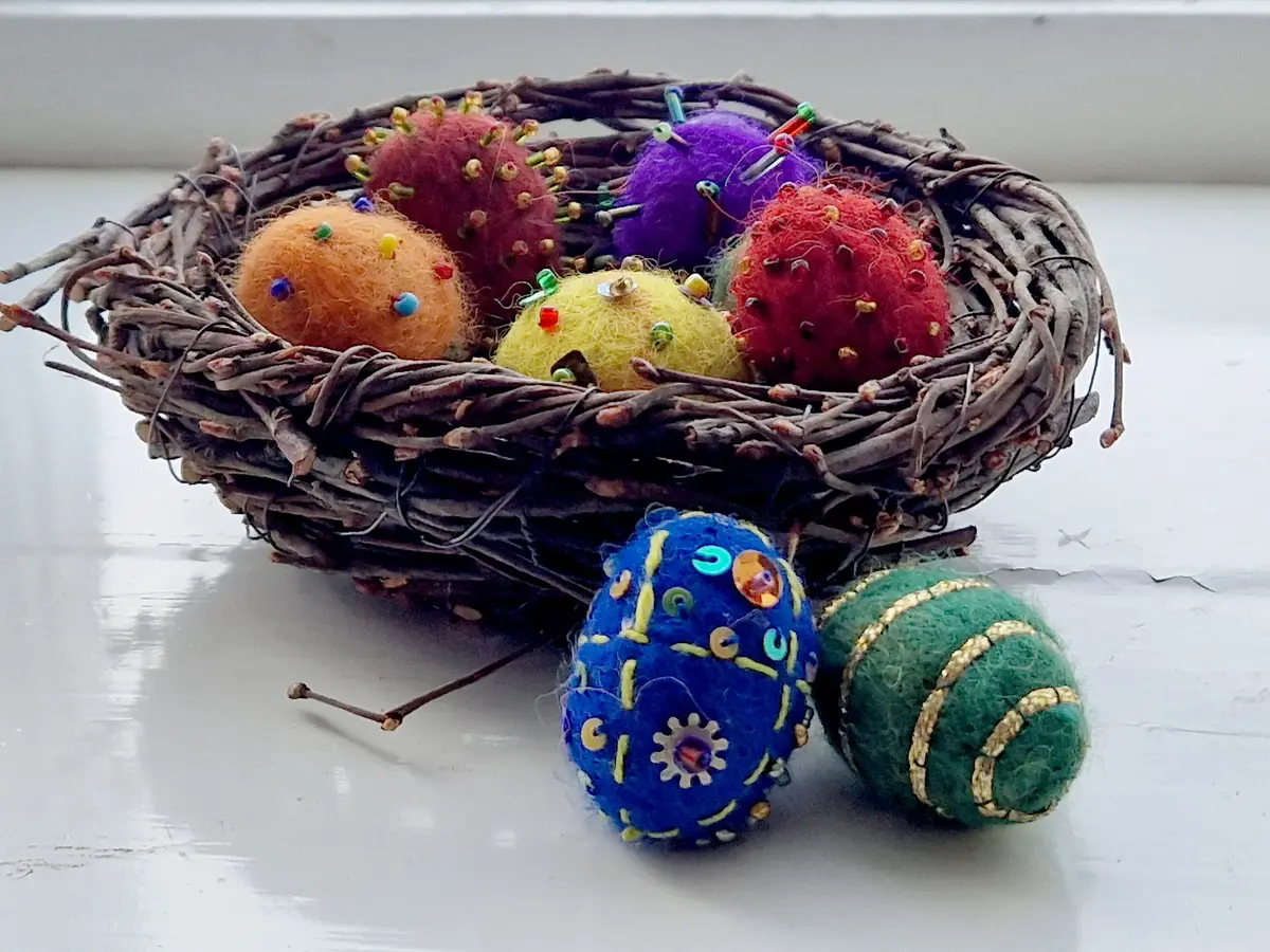 Tovade ägg med dekoration av pärlor och stygn i fågelbo av björkris