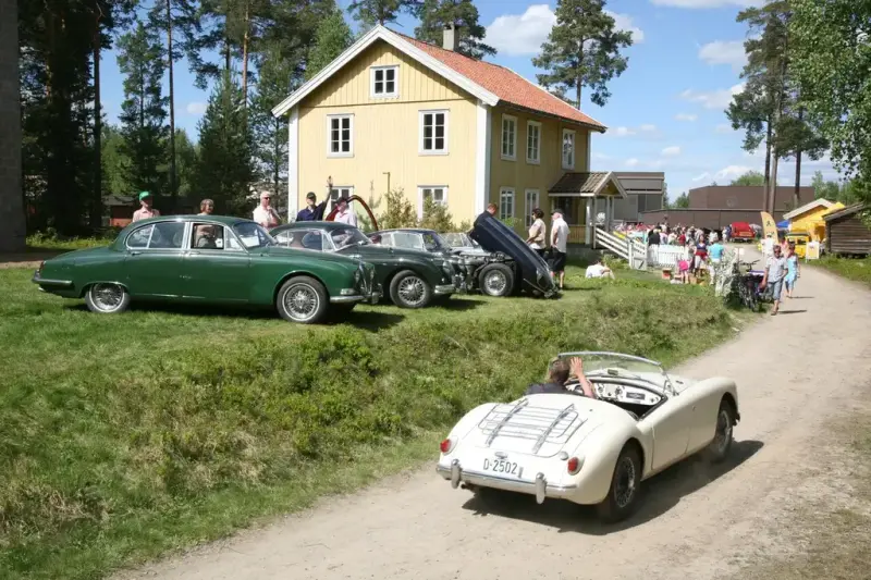 oppstilte veteranbiler og gult eldre hus 
