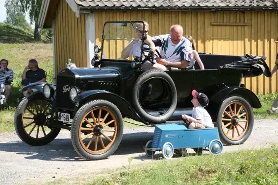 veteranbil og et barn i olabil ved siden av