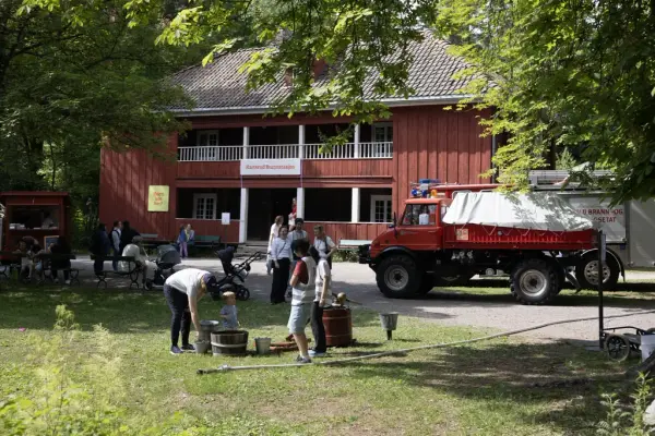 Familier deltar i aktiviteter foran Karterud Brannstasjon, med en veteranbrannbil parkert i bakgrunnen.