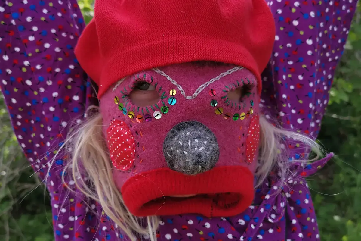 Barn med tovad och broderad mask