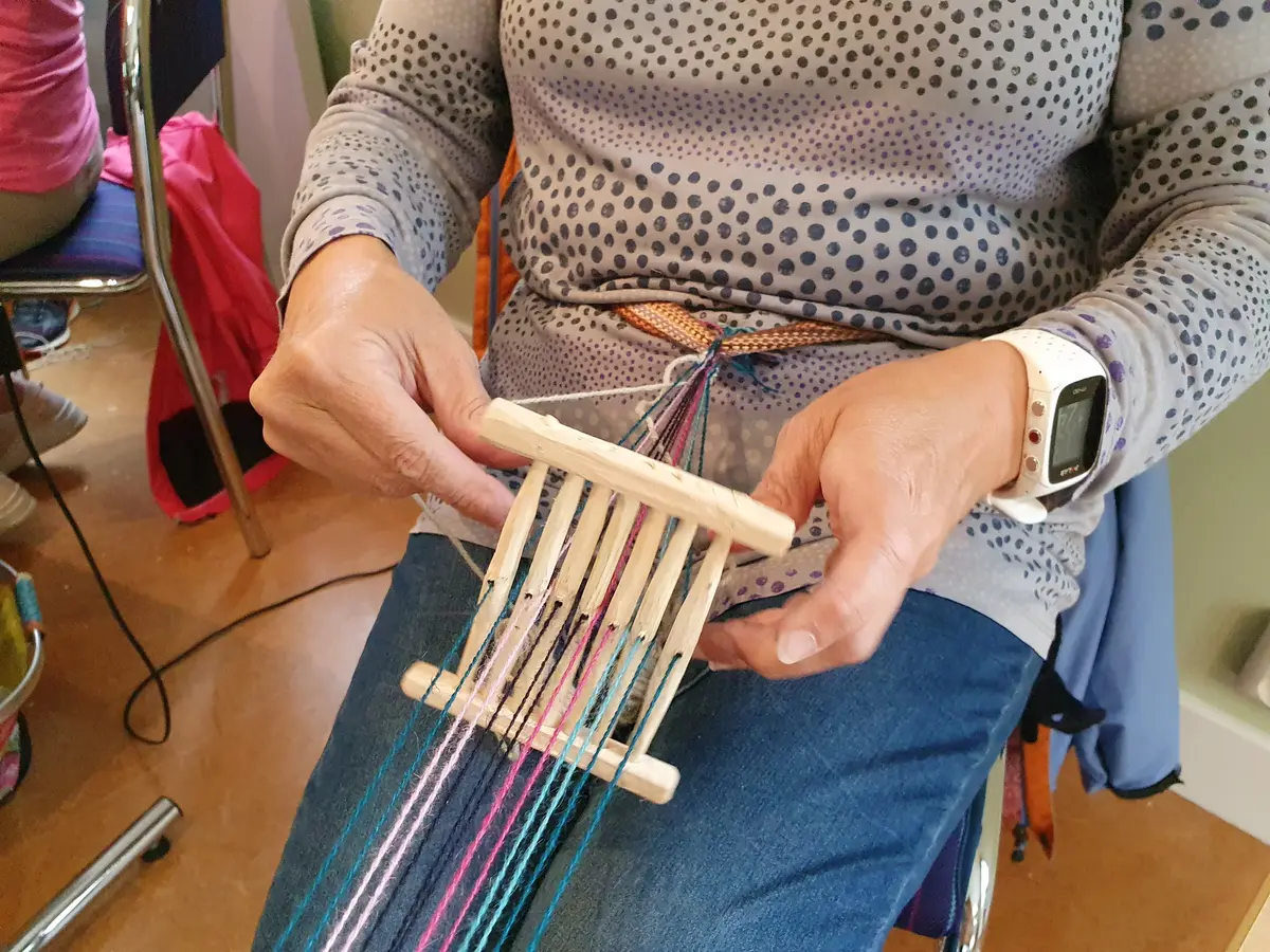 En täljd bandgrind och kvinna som väver