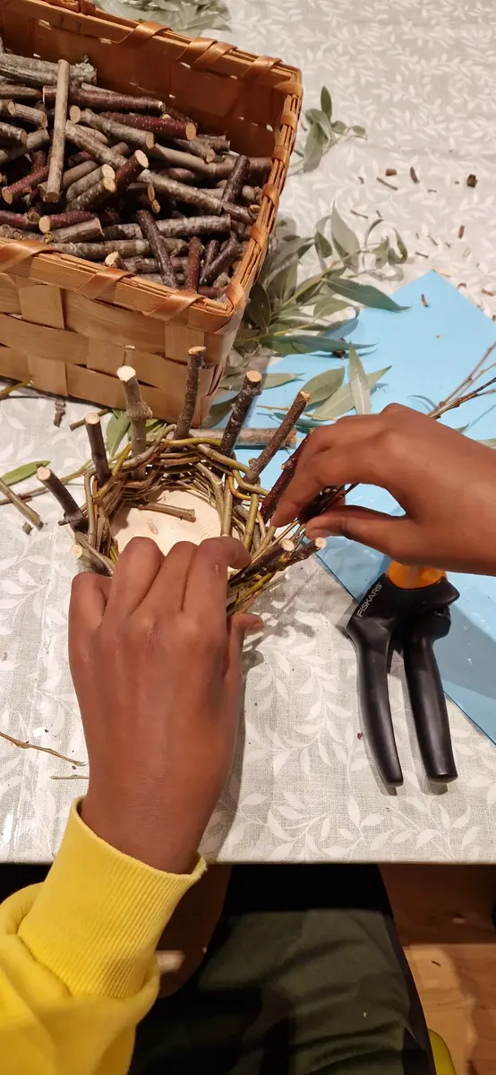 Barnhänder som flätar korg 