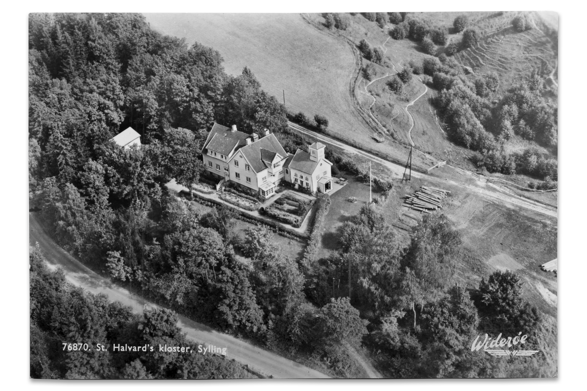 St. Hallvard kloster 1954, to år før det ble lagt ned som novisiat. Biskop Fallisze hadde valgt sitt sted med omhu. Høyt, fritt og avskjermet med vakker utsikt over åkrer, åser og vann. Et sted for ro, meditasjon og fordypelse. Bildet er tatt på den tiden brunkuttemunken, pater Leo van Eekeren var novisiatets overhode.