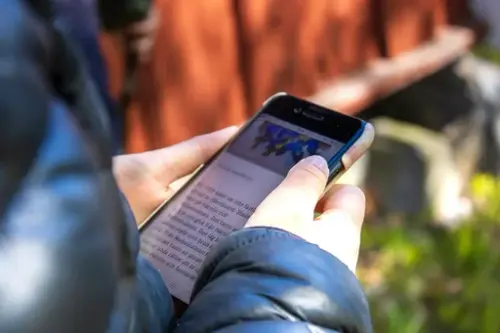 Ett barns händer håller i en mobil och läser om rysshärjningarna.