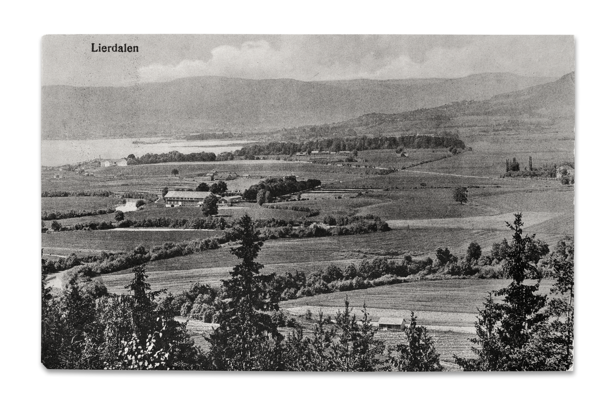 Utsnitt av Lierdalens ytre deler ca. 1920. I øvre midtre del øyner vi Osloveien som en tynn, hvit stripe. Der den forsvinner ut mot høyre bildekant, ser vi litt av hovedbygningen på Søndre Huseby. Gårdsbruket med den store låven midt i bildet er Tandberg-Huseby.