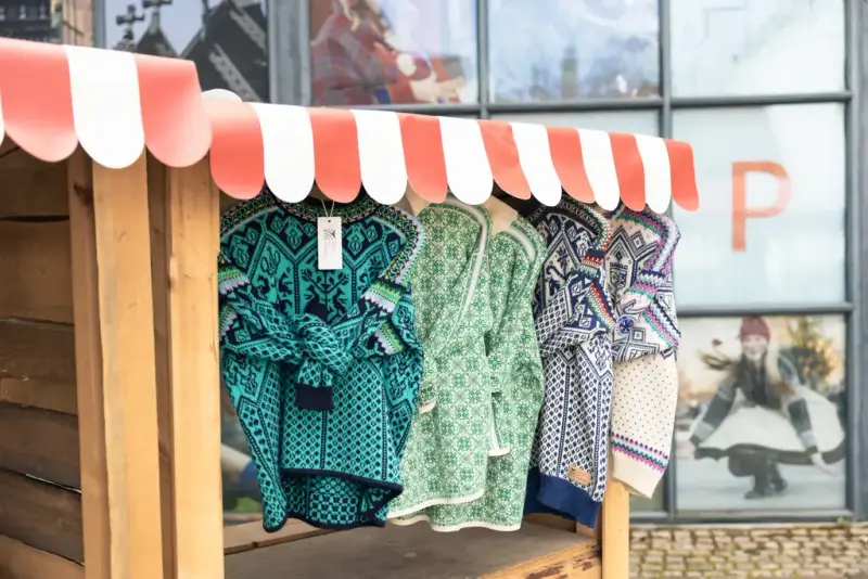 Tradisjonelle ullkåper og strikkegensere i mønstre og farger, utstilt utenfor museumsbutikken på Norsk Folkemuseum.