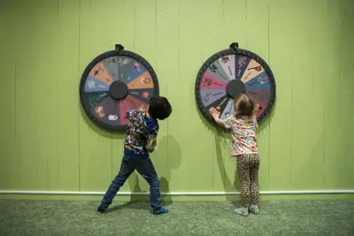 Två barn i Småfolk som snurrar på hjul som sitter på väggarna