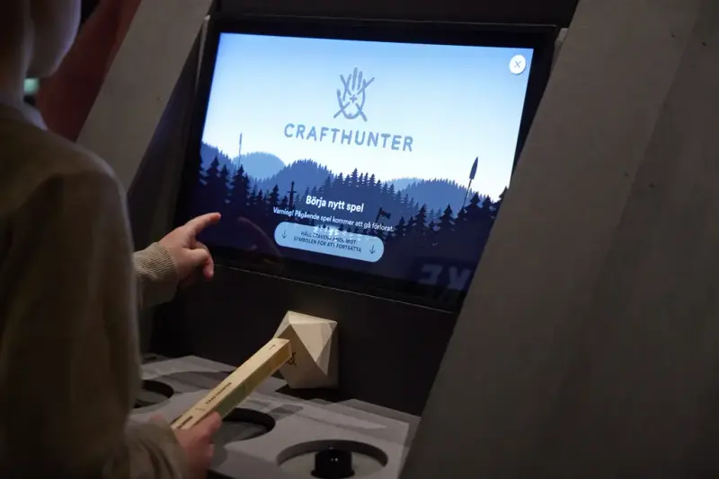En del av ryggen på ett barn och en skärm som visar startsidan i crafthunter. 