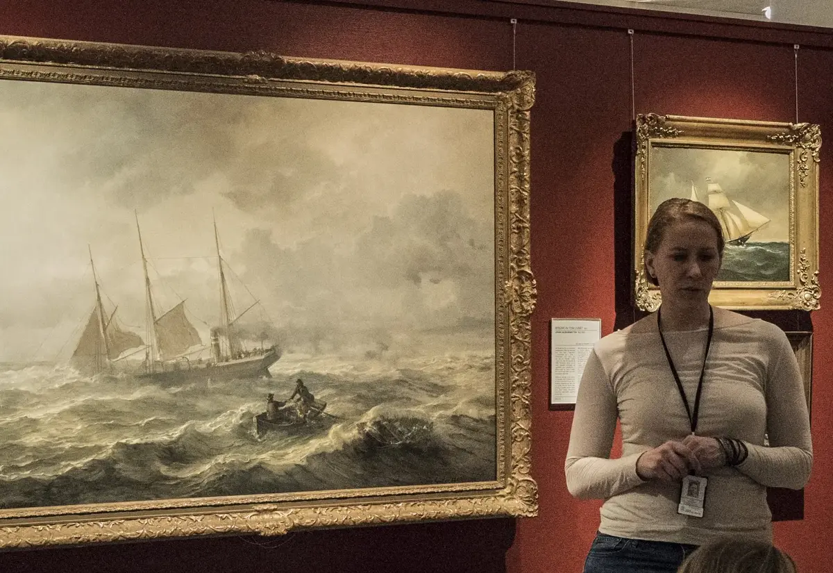Formidler holder omvisning foran maritimt maleri i galleri på Norsk Maritimt Museum.