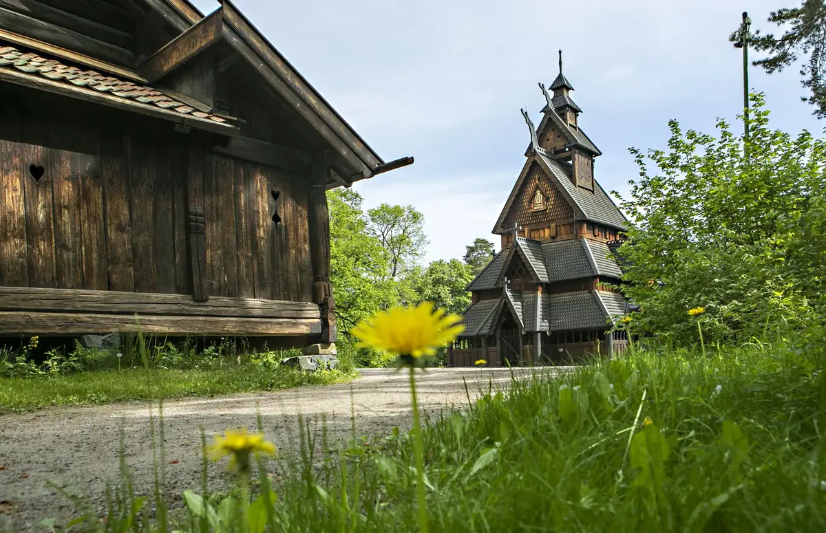 Stavkirken fra Gol i friluftsmuseet på Norsk Folkemuseum, omgitt av grønt løvverk.