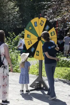 Lite barn deltar i lykkehjulaktivitet sammen med en OBOS-ansatt under Sankthansfestivalen på Norsk Folkemuseum.