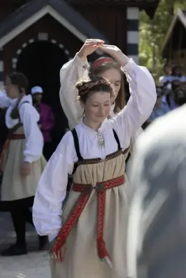 o jenter i bunad danser folkedans under Sankthansfestivalen på Norsk Folkemuseum.