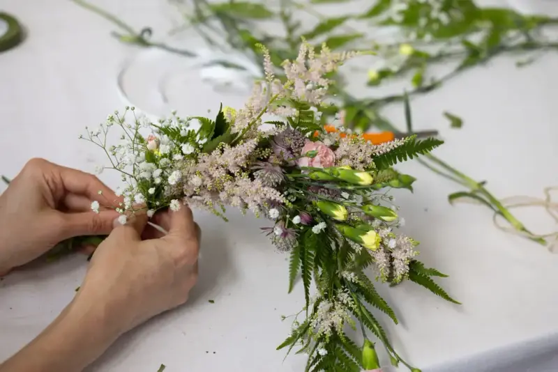 Hender som lager blomsterkrans med markblomster under Sankthansfestivalen på Norsk Folkemuseum.
