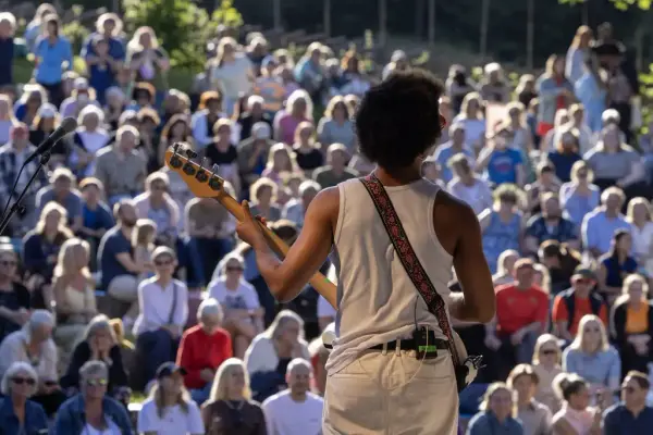 Musician on stage in front of a large and engaged audience during the Midsummer Festival at Norsk Folkemuseum.