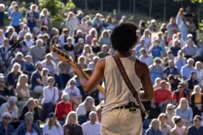 Musician on stage in front of a large and engaged audience during the Midsummer Festival at Norsk Folkemuseum.
