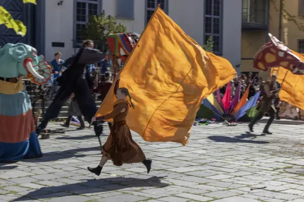 Performers with large costumes and colorful flags in motion during a Stella Polaris show at the Midsummer Festival.