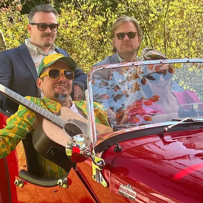 Grünerløkka Festorkester: tre menn og en kvinne sitter i en rød bil. 