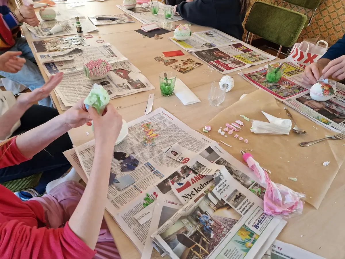 Personer som sitter runt ett bord fullt med sockeräggspyssel