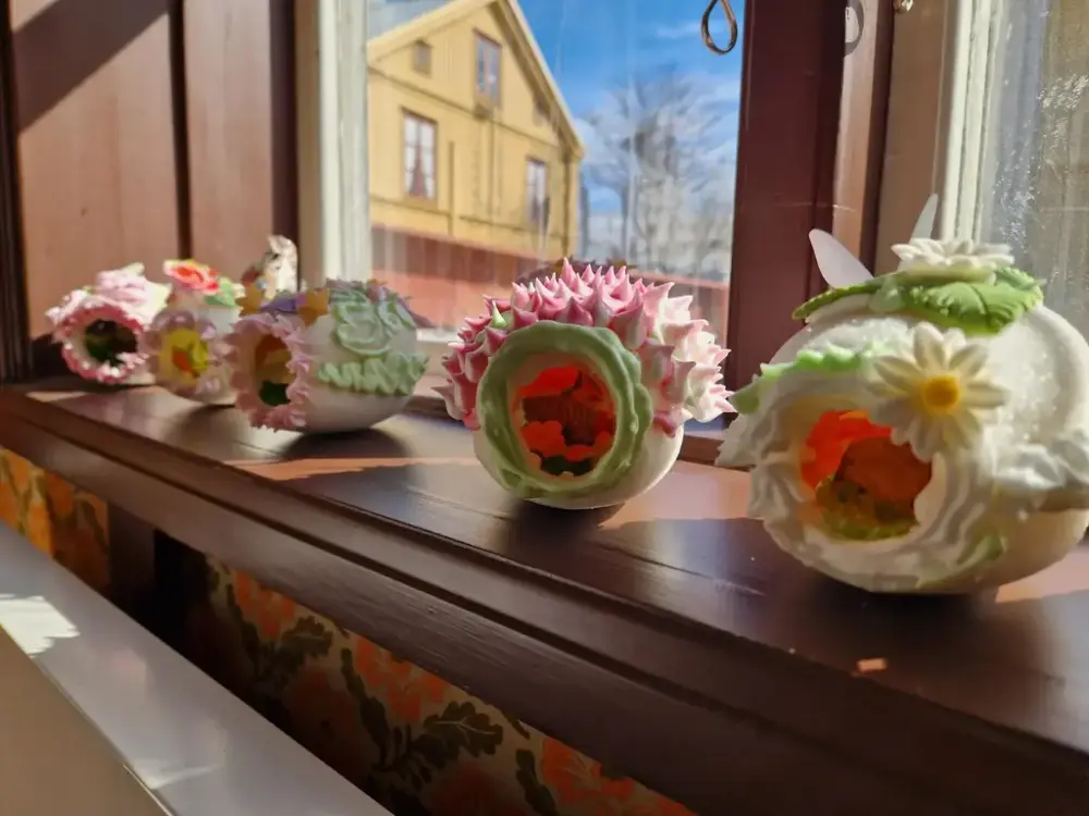 Fem dekorerade sockerägg utplacerade vid ett fönster.
