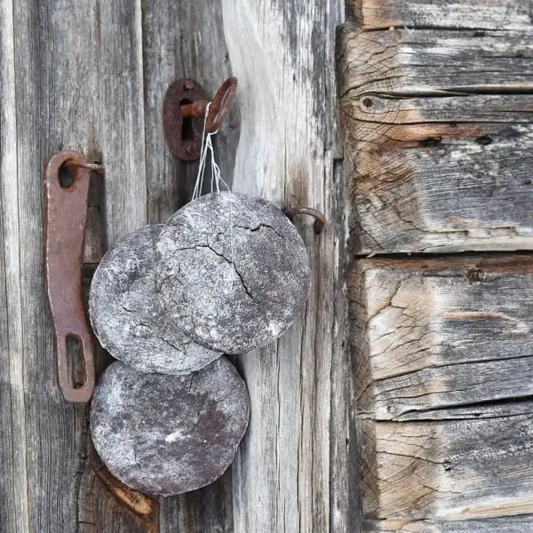 runde brød henger til tørk på snor på døra til et gammelt stabbur