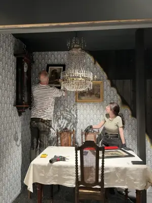 Två personer står i en monter och hänger upp föremål.