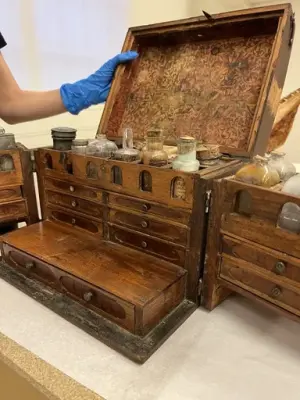 En låda av trä med flera fack och flaskor. 