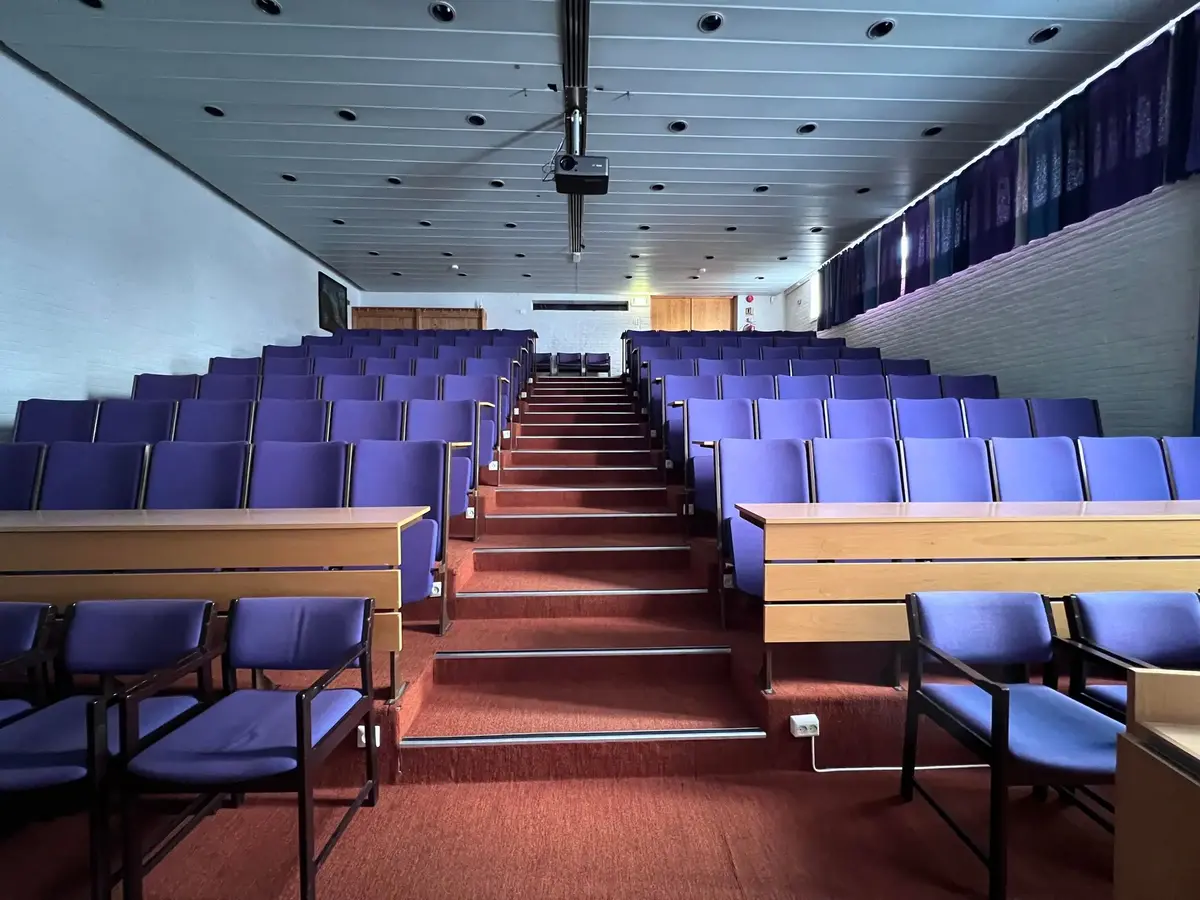 Auditorium med stoler i amfi og midtgang.