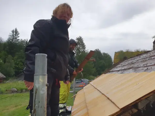 To personer står ved siden av gammelt tak, hvor det blir lagt nye treplater. 