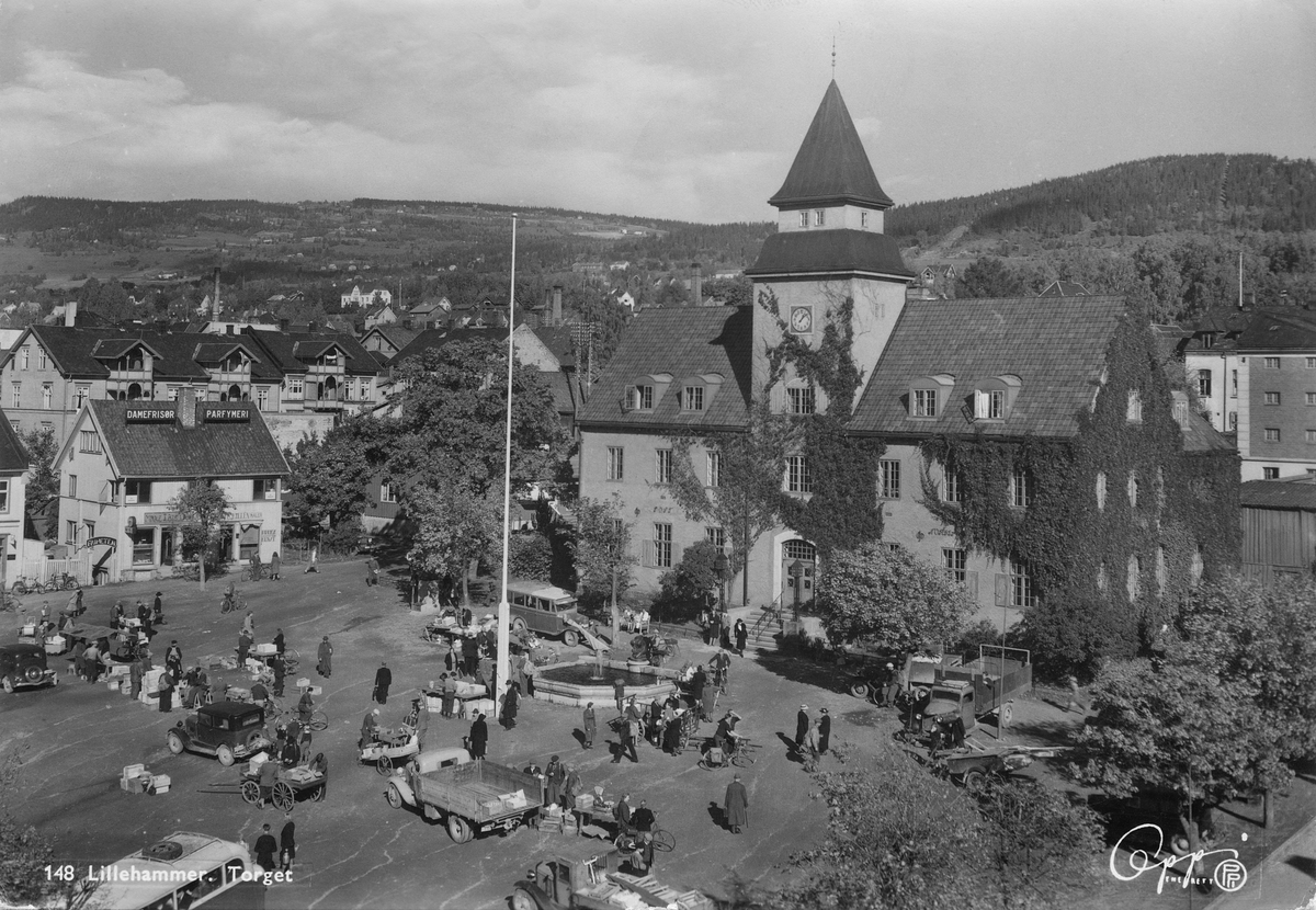 Lillehammer. Prospektort. Torghandel på Stortorget med Norges Bank i bakgrunnen. På Stortorget 3 holdt Killèn til med Bruktkunst, antatt en kafè kalt "Friheten", og parfymeributikken til Marie J Bjelland