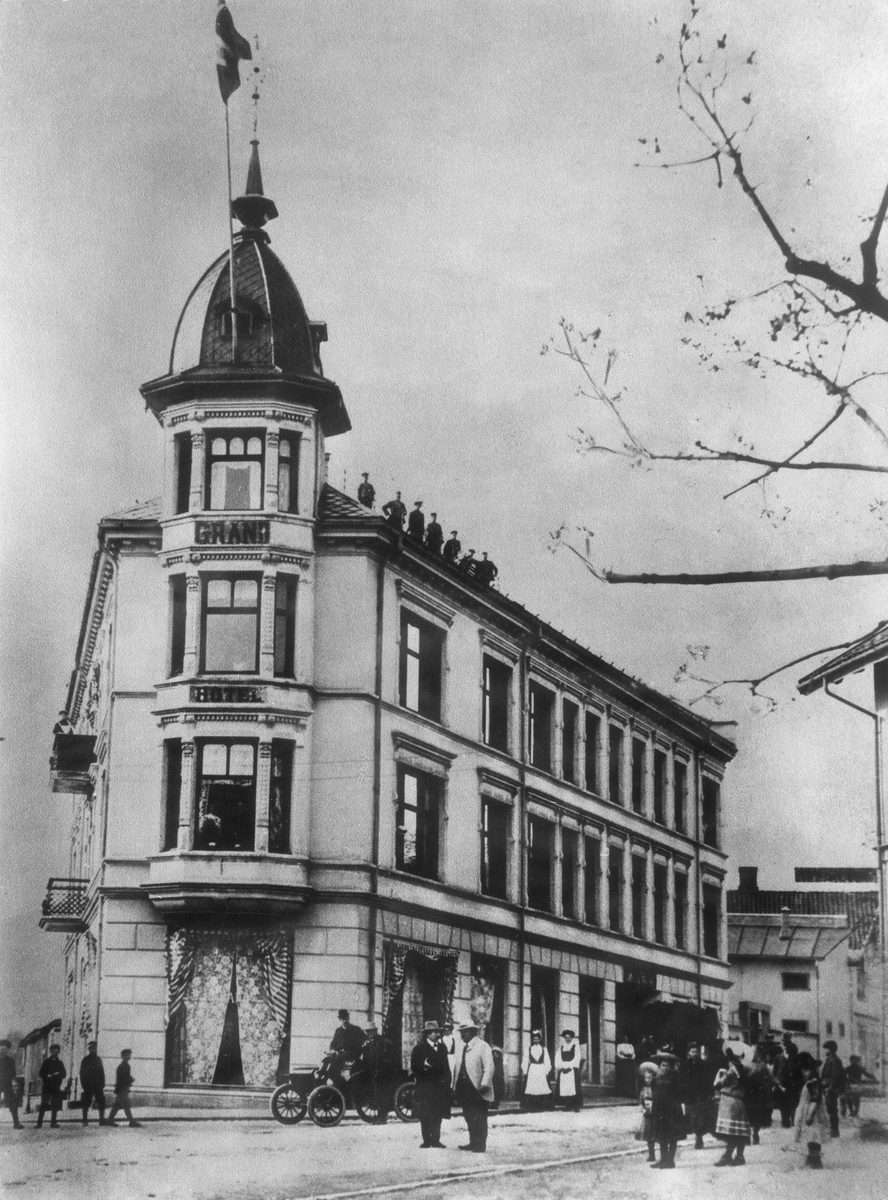 Oppland, Lillehammer. Grand hotel på hjørnet av Kirkegata og Nymosvingen. En av mennene utenfor bygningen er pipefabrikant Larsen som fikk hotellet bygd