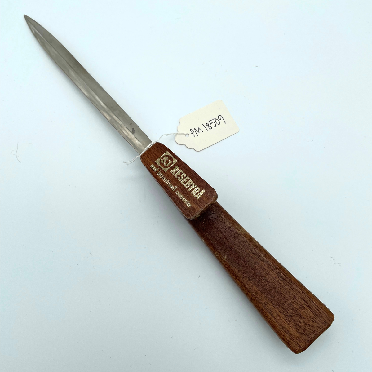Brevkniv rostfritt stål med handtag i teak.

Text på handtaget: SJ RESEBYRÅ med internationell reseservice