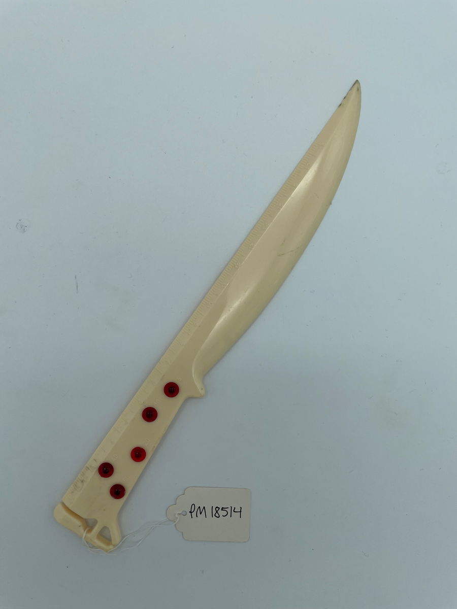 Brevkniv i plast med text i guld: "ACMA Axel Christiernssons Maskin Aktiebolag".

Brevkniven kan också användas som brevvåg. Det finns ett jack i ena änden där man kan klämma fast ett brev (text: Insert letter) och 5 stycken röda knappar som går att snurra på. Knapparna har olika viktangivelser (5g, 10g, 20g, 40g och 50g) för att mäta brevets tyngd. Man klämmer fast brevet och håller med tum och långfinger om en knapp för att hitta jämnvikt. Se bild två.

Brevkniven fungerar även som linjal. Längs brevknivens ena långsida finns en måttstock med mm-skala (0-18 cm).