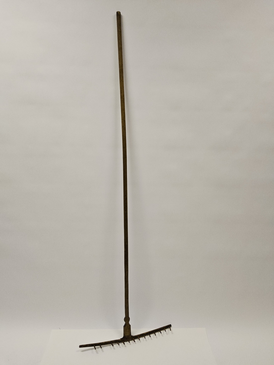 Räfsa med helt skaft. Rika sniderier, bl.a. rosett i karvsnitt samt stiliserade bladornament. På undersidan järnvägslatpp "Skultorp". Inköpt på auktion.