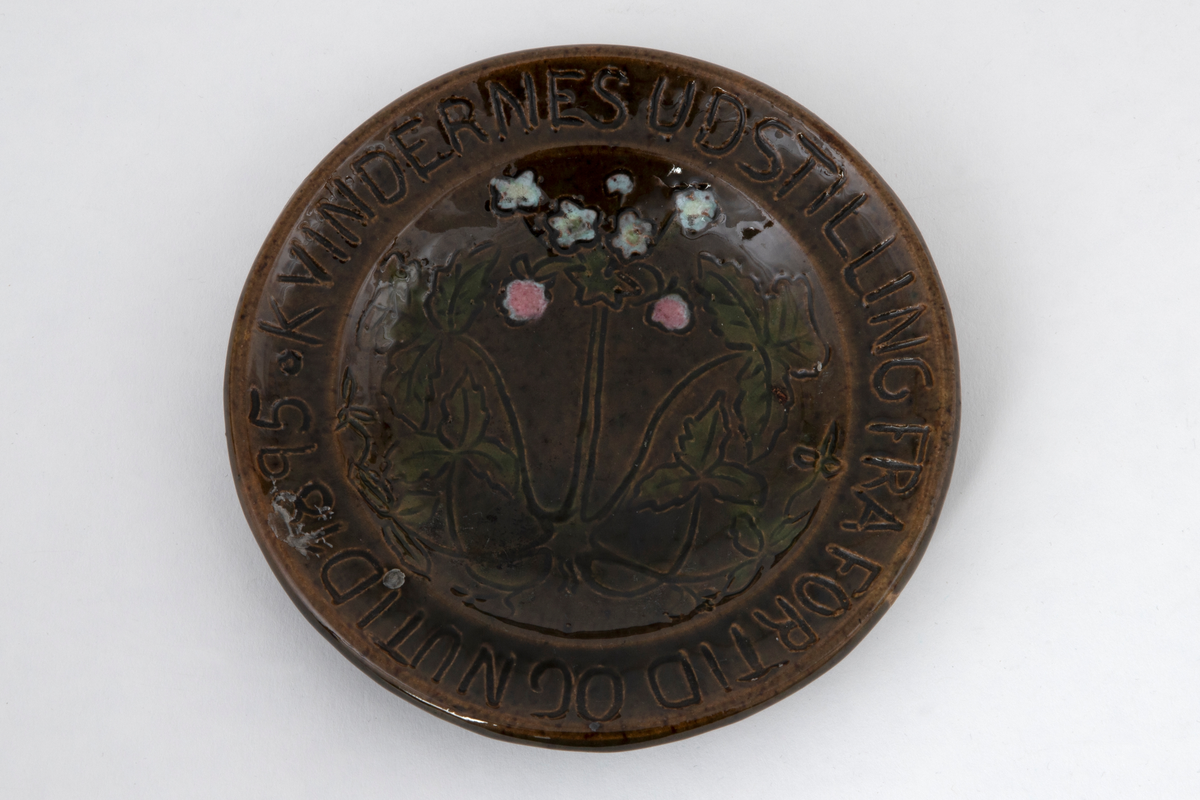 Lite fat i glasert leirgods. Oversiden er glasert, undersiden uglasert med rødbrunt gods. I bunnen på oversiden er det risset et plantemotiv med blomster og blad. Dekoren er gul.