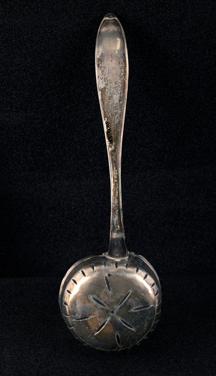 Sukkerdrysseskje av sølv. Dyp, rund skje med gjennombrutt dekor i bunn. Stemplet, se foto