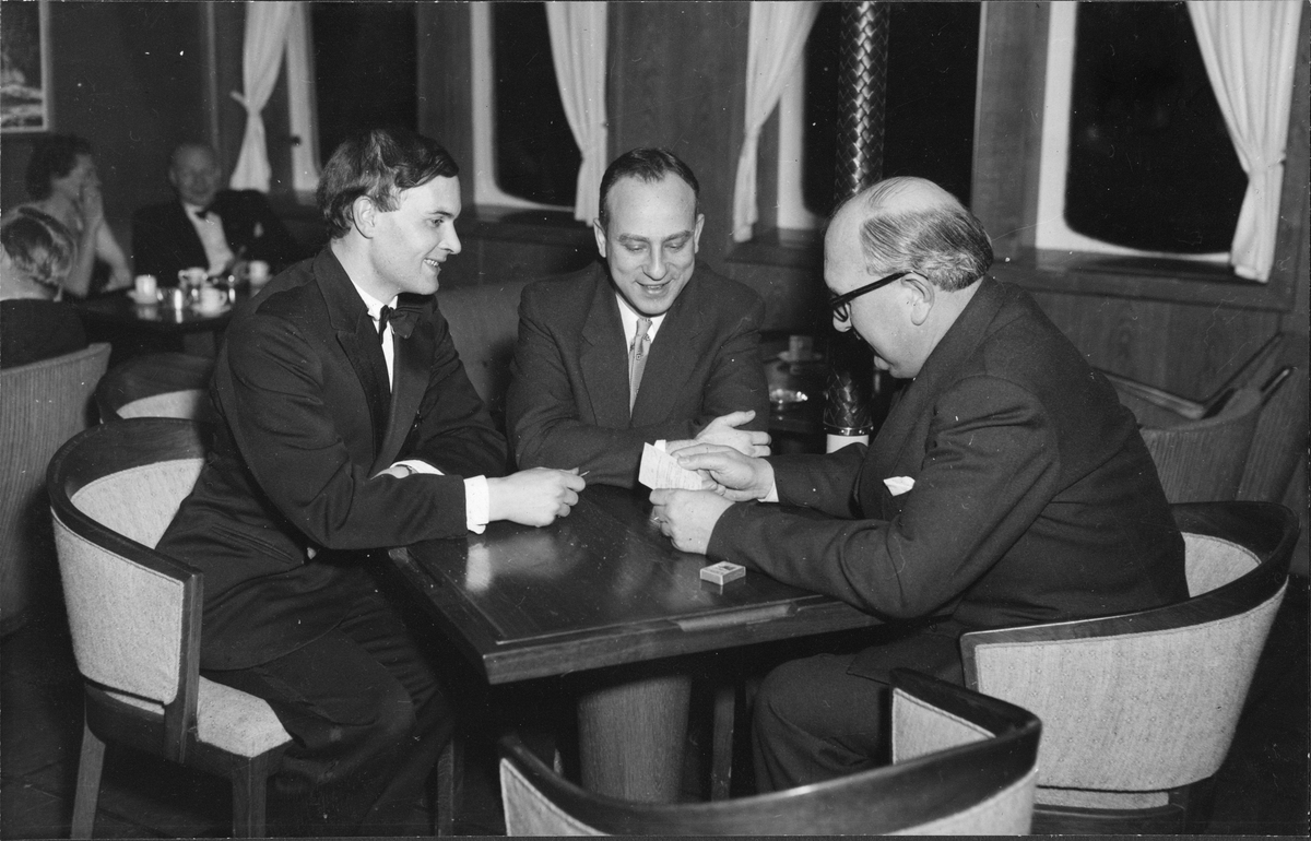 Festkledde passasjerer hygger seg i salongen på MS METEOR. F.v. Derek Goozée, Professor Melvil White of Brooklyn, Fred Smith of Grimsby.