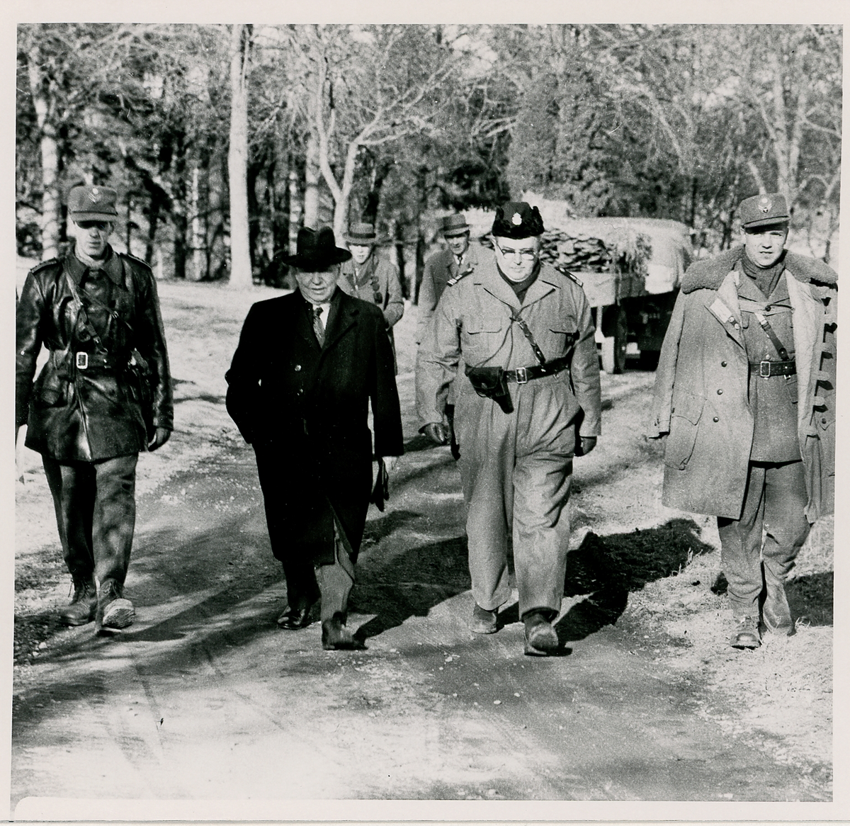 Några herrar vandrar längs en grusväg. I mitten landshövding Thorwald Bergquist och kommissarie Sture Sandell. De övriga okända.
Spaning efter "Jack" någonstans i Kronobergs län, 1959. Reportagebild.