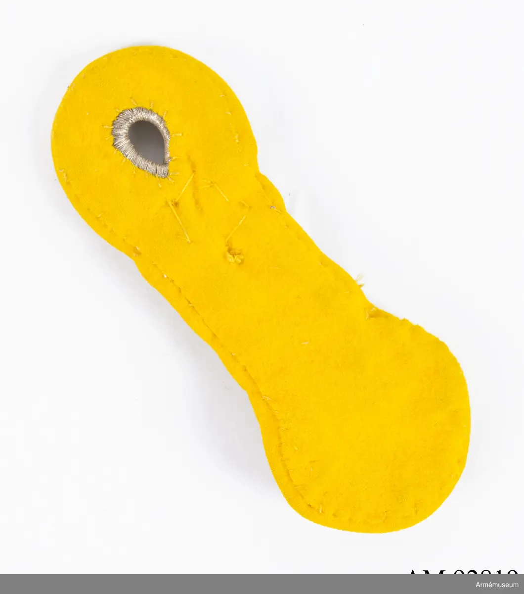 Axelträns i silver med guldfärgade dekorationer på gul botten.

Axeltränsen är gjord av dubbelt silverfärgat beläggningssnöre av metalltråd i en platt flätad form med en tredubbel knut nederst, ovanför detta tre dubbla flätningar och en ögla som bildar ett knapphål. Ovanpå denna flätade form är fastsytt två femuddiga stjärnor samt nederst en 1:a och kung Gustaf V:s (förgyllda?) namnchiffer i mässing.
Allt samman är sedan fastsytt på en botten av gult kläde.