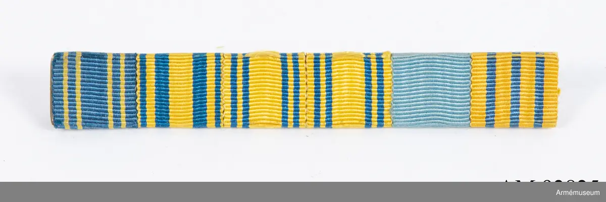 Släpspänne med ordensband från diverse svenska ordnar.

Spännet består av ett långsmalt metallbakstycke med band från 6 olika svenska ordnar eller minnestecken monterade på framsidan. På baksidan en nål för fastsättning.
