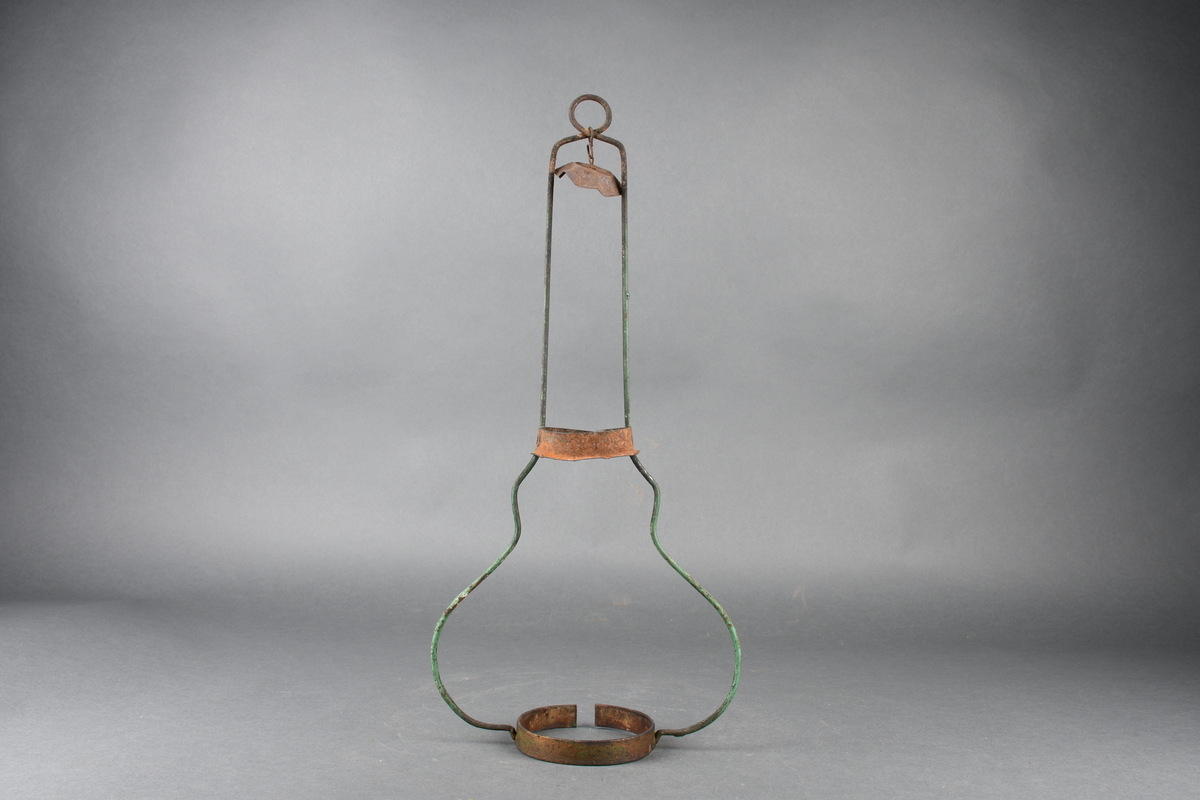 Oljelampe bestående av stativ av metall, skjerm av blikk malt grønn på oversiden og hvit på undersiden, parafinbrenner av glass, metall og veke av vevet tekstil, samt et lampeglass.