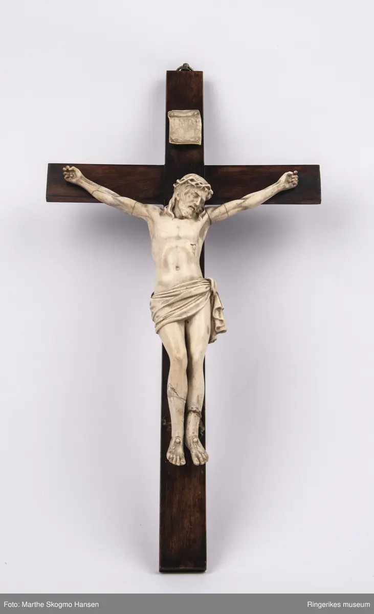 Kors i mørkt tre med oppheng og hvit jesusfigur.