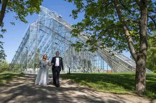 Et brudepar vandrer sammen en sommerdag foran glassmonteret på Anno Domkirkeodden